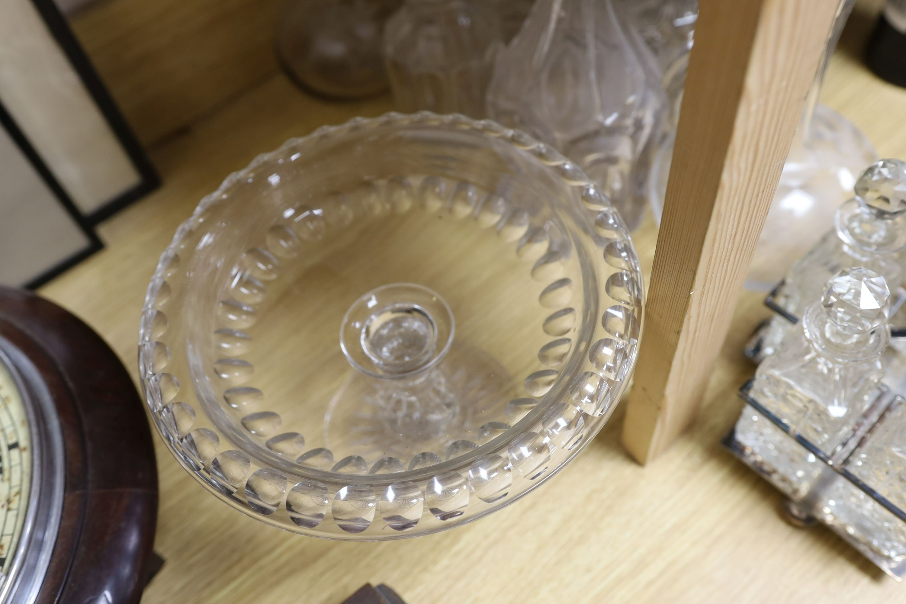 Sundry glassware including a six bottle cruet set on a plated stand, a Victorian cut glass jug, a pair of long neck decanters, five other decanters and a glass cake tazza